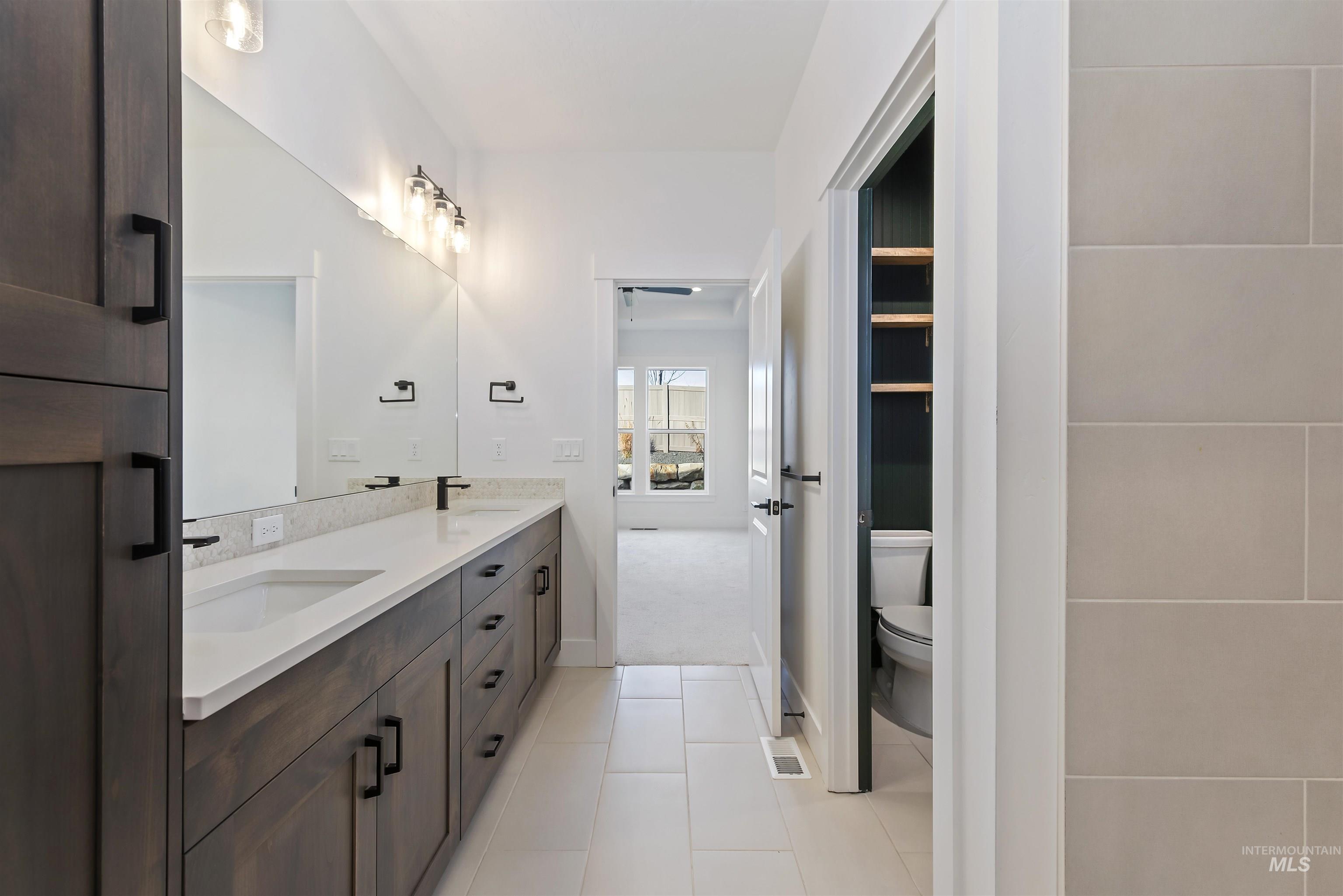 Bathroom with double vanity, light tile patterned floors, and light colored carpet