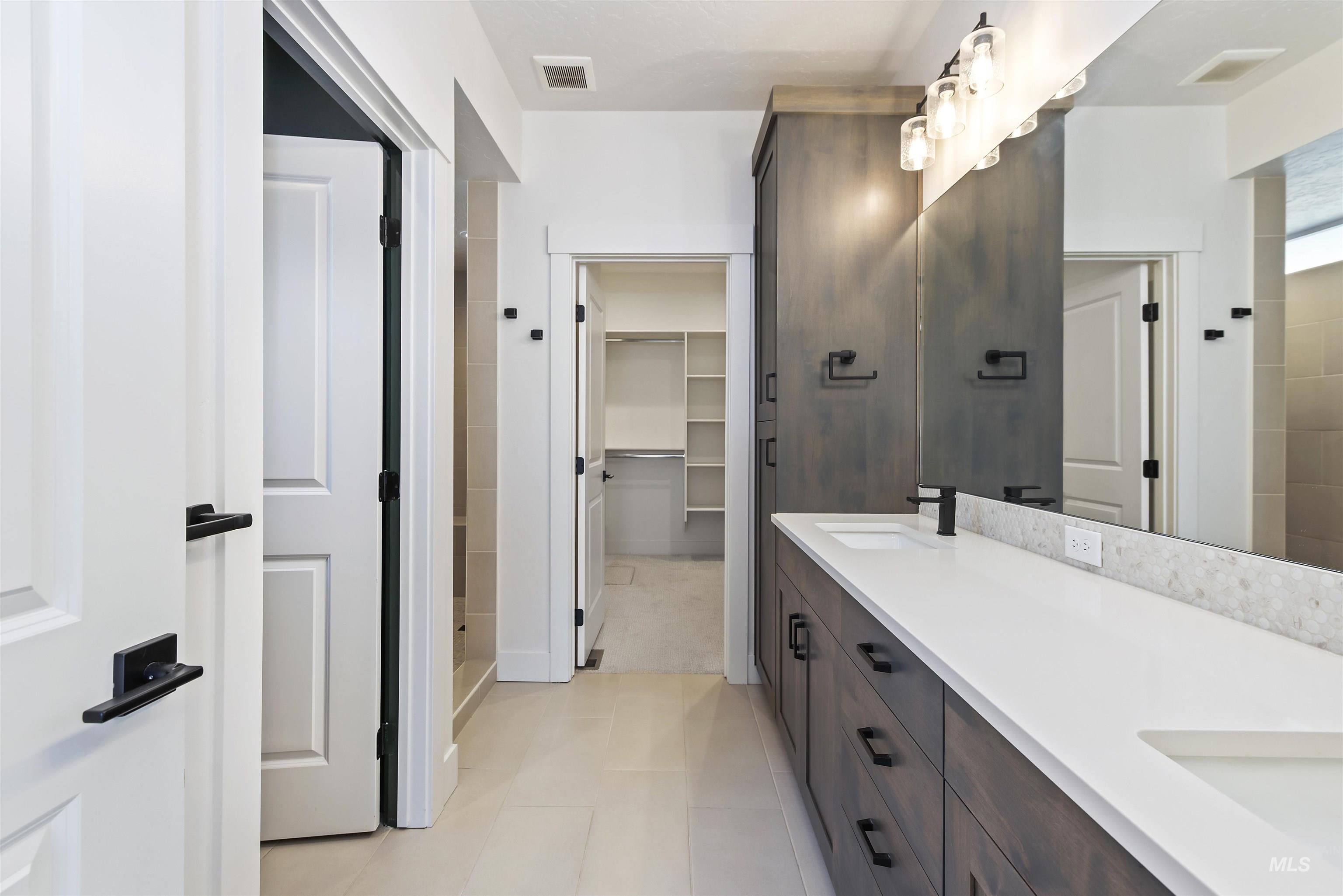 Full bath featuring double vanity, a spacious closet, and light tile patterned flooring