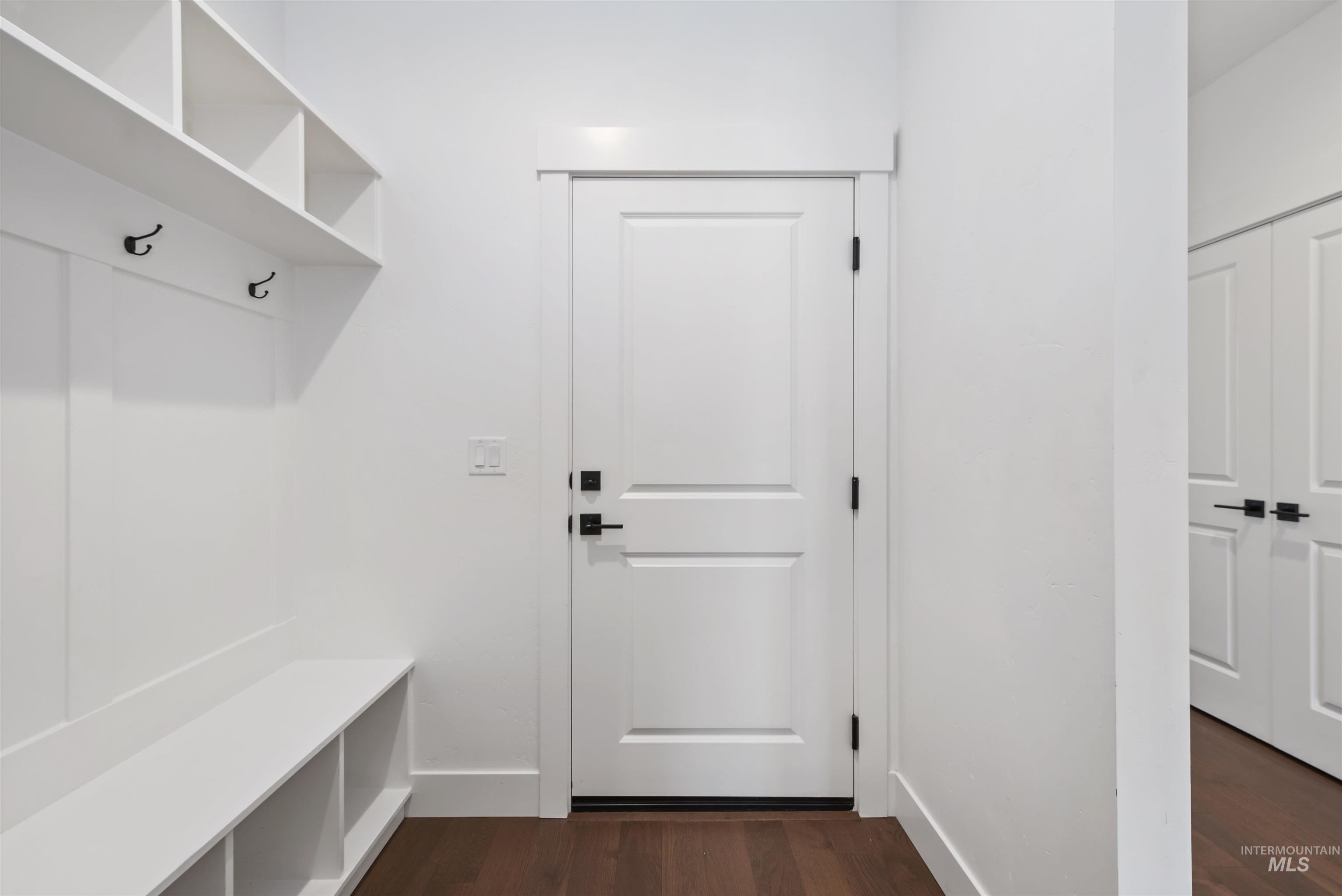 Mudroom featuring dark wood finished floors and baseboards