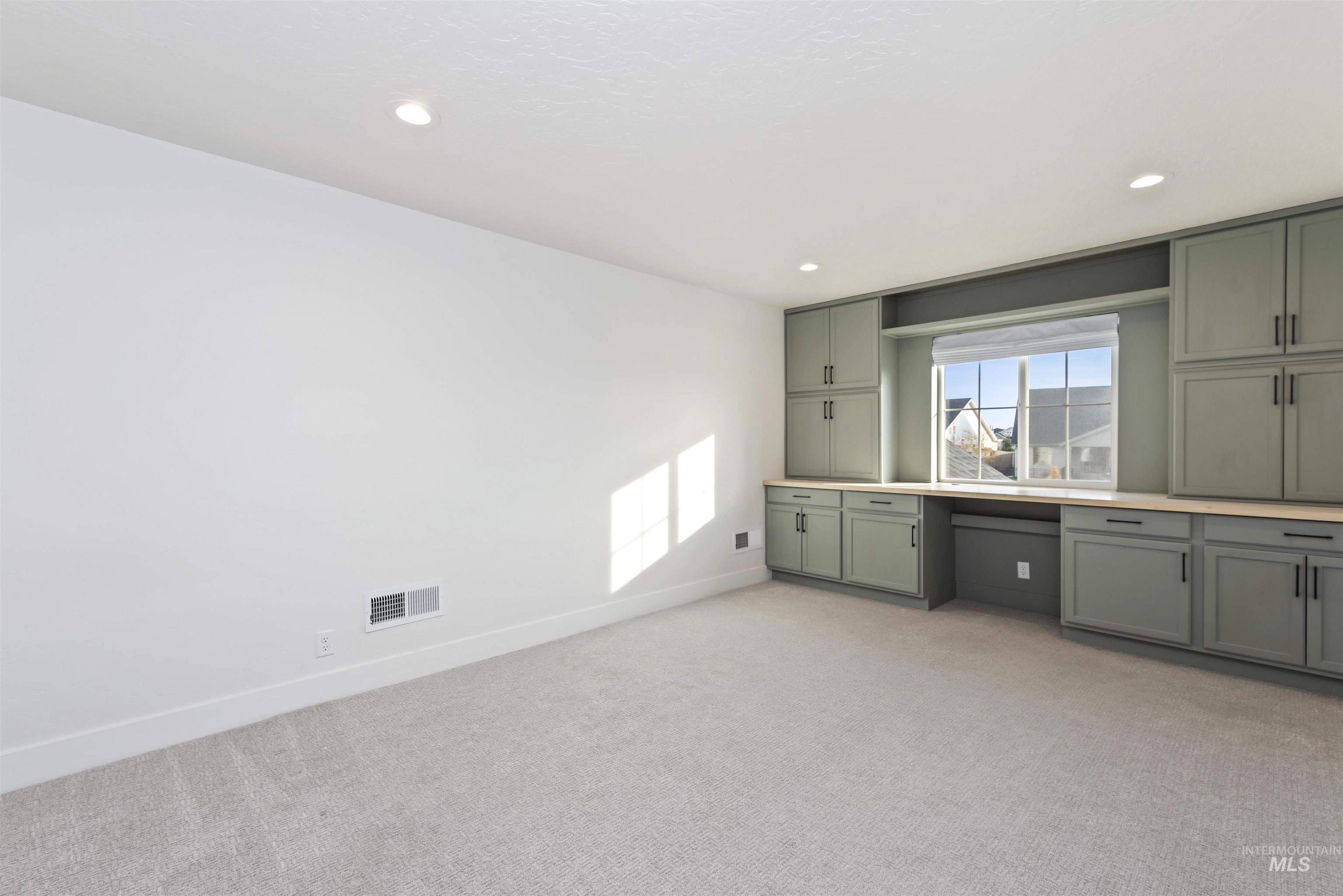 Kitchen with light carpet, light countertops, recessed lighting, gray cabinets, and built in desk