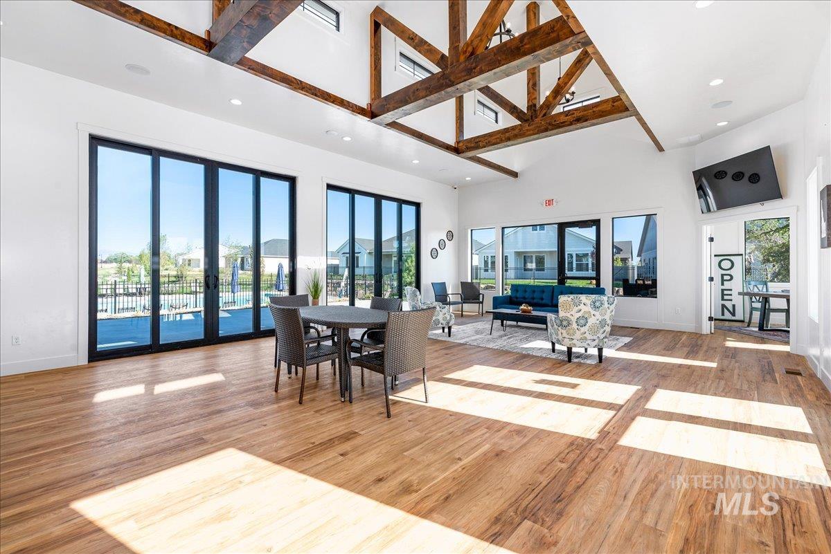 Dining room featuring a high ceiling, healthy amount of natural light, beamed ceiling, light wood-style flooring, and recessed lighting