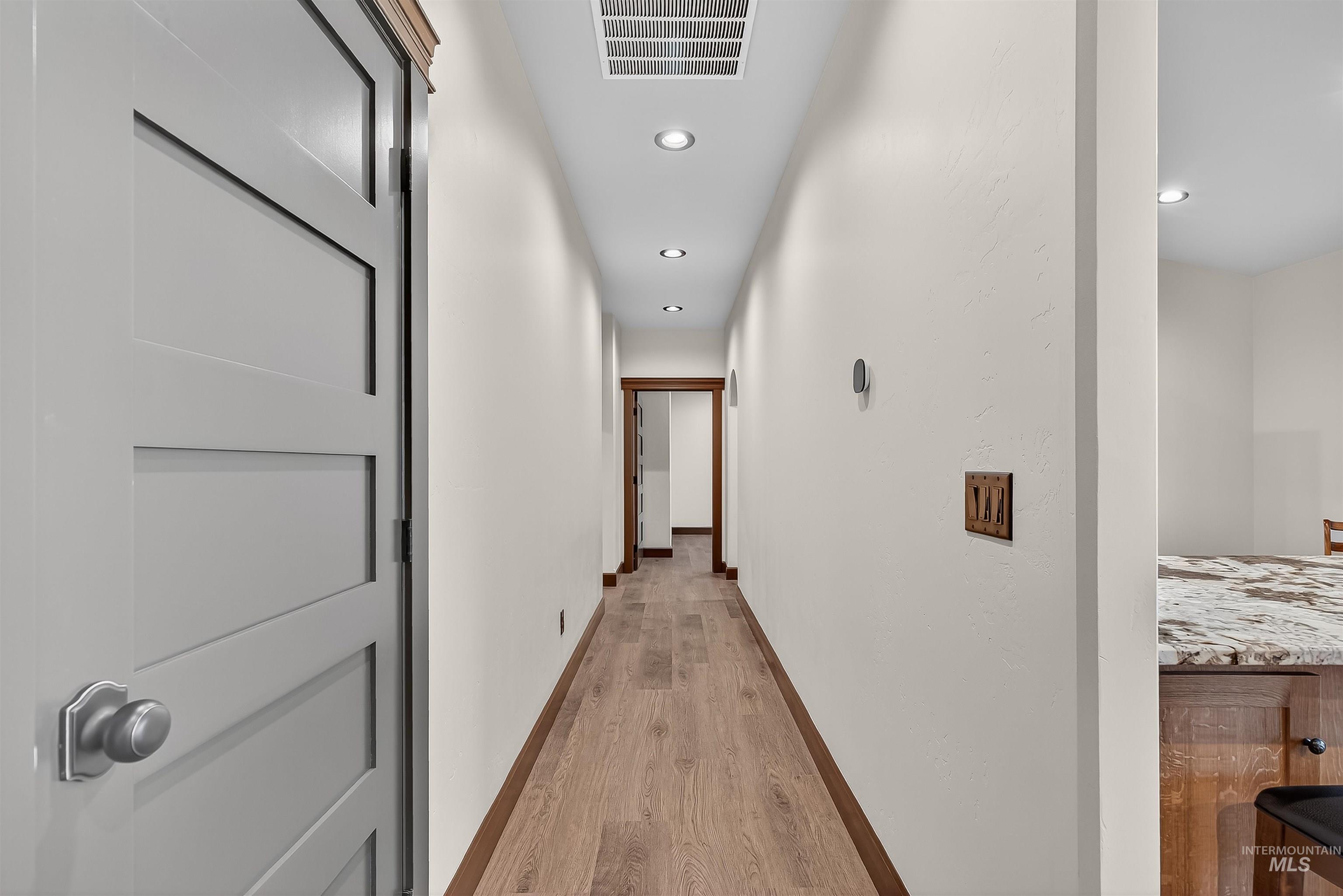Hallway with light wood-style flooring and recessed lighting
