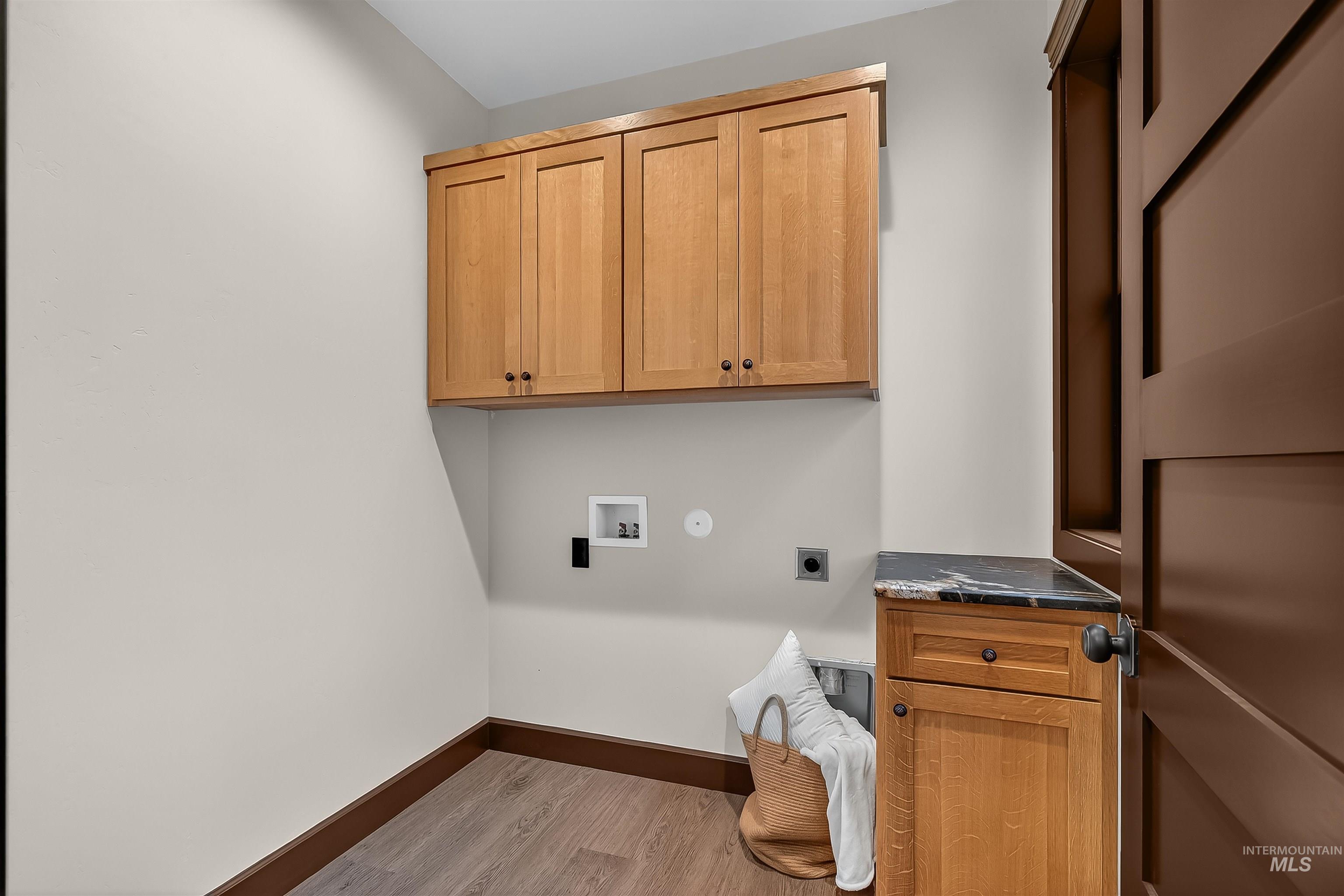 Laundry area featuring hookup for an electric dryer, light wood-style floors, hookup for a washing machine, and cabinet space
