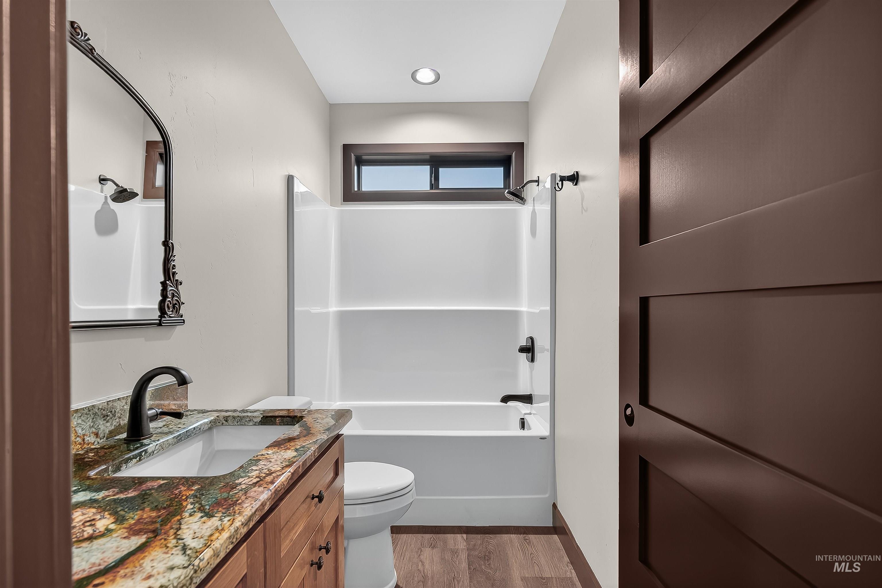 Bathroom with vanity, light wood-type flooring, and  shower combination