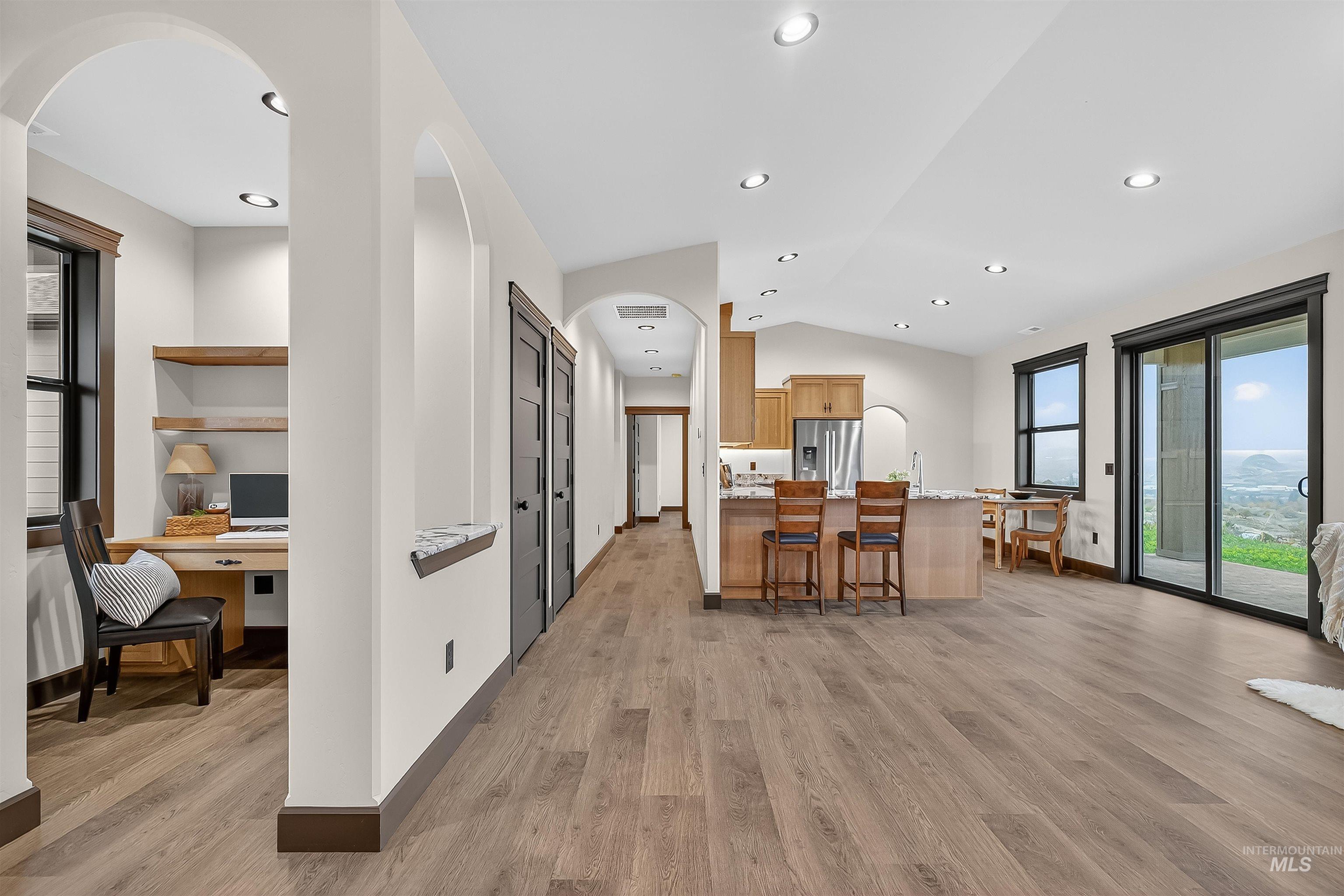 Kitchen featuring arched walkways, built in study area, vaulted ceiling, a kitchen breakfast bar, and light wood finished floors
