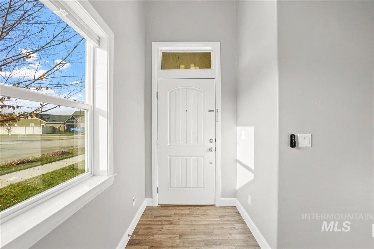 Doorway to outside with baseboards and wood finished floors