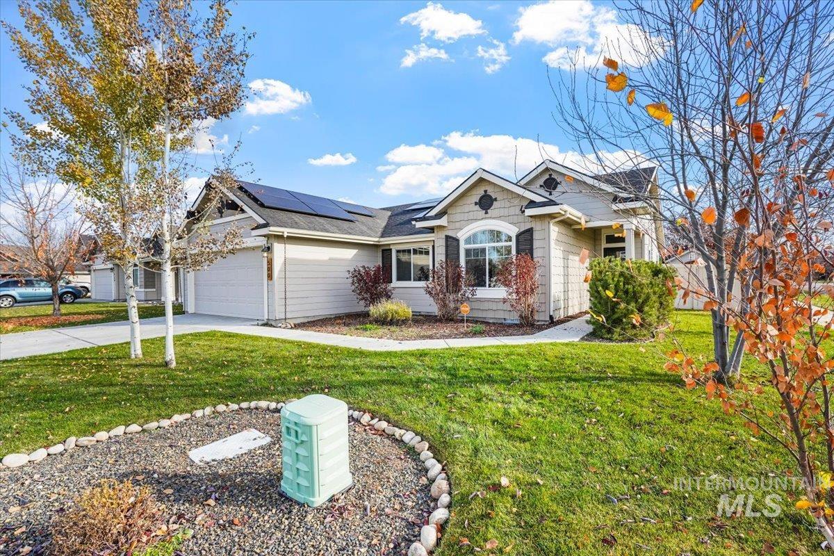 Single story home with a front yard, solar panels, driveway, a garage, and a shingled roof