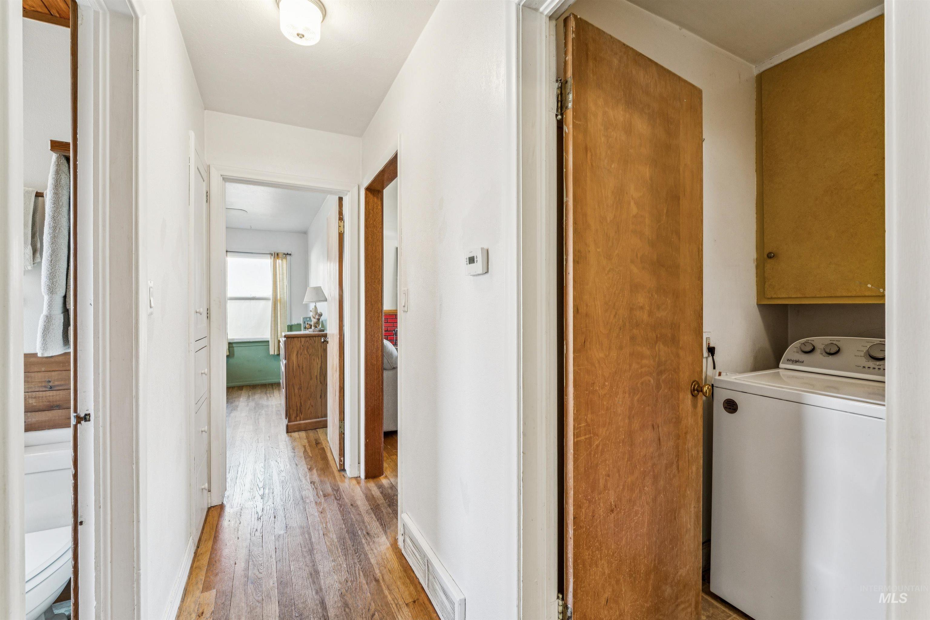 Laundry room with washer / clothes dryer, light wood-style flooring, and cabinet space