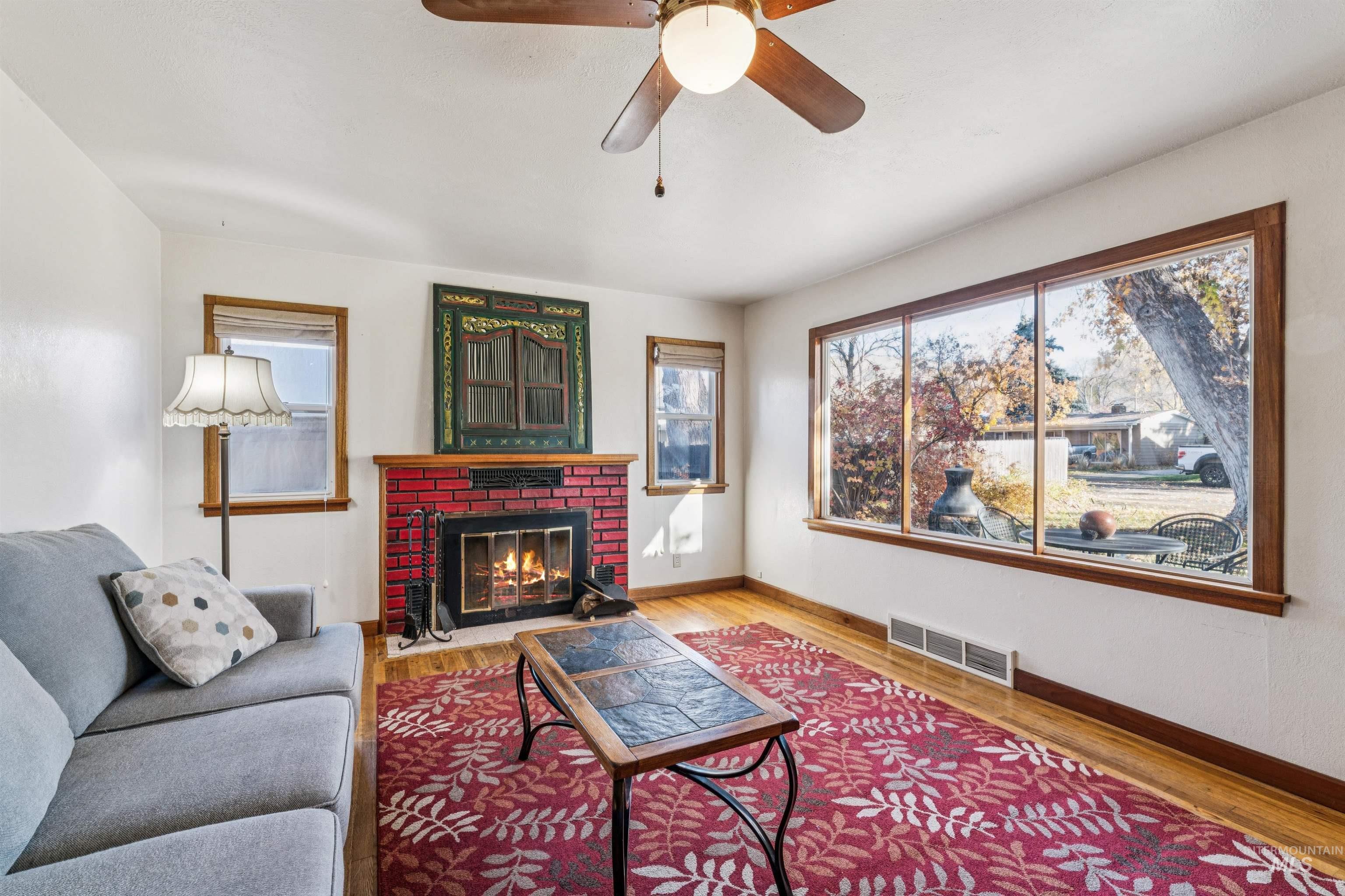 Living area featuring wood finished floors, healthy amount of natural light, a fireplace, and a ceiling fan