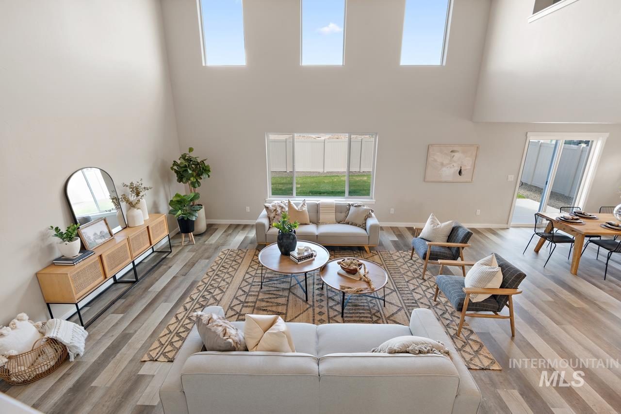 Living room featuring plenty of natural light, a towering ceiling, and light wood-style floors