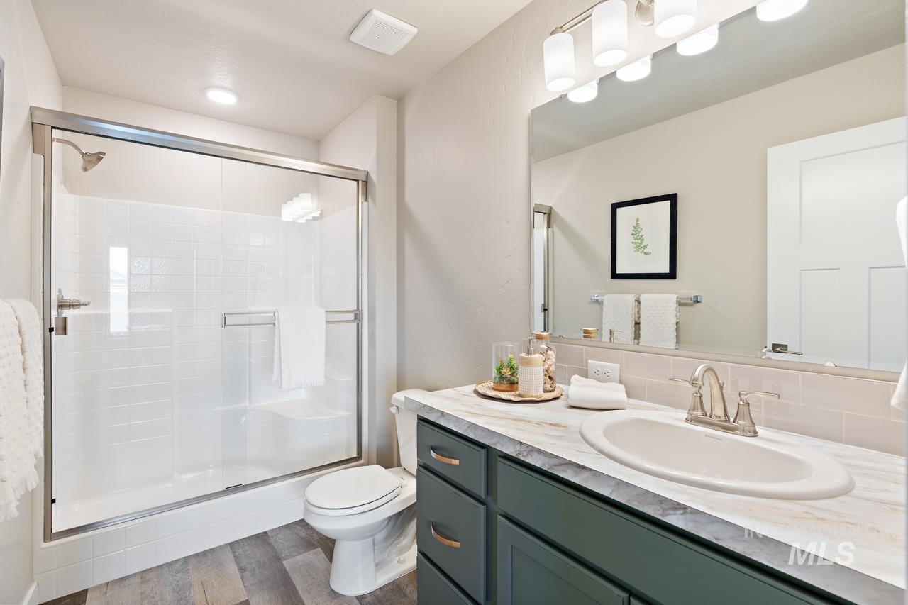 Full bath featuring a stall shower, vanity, backsplash, and wood finished floors