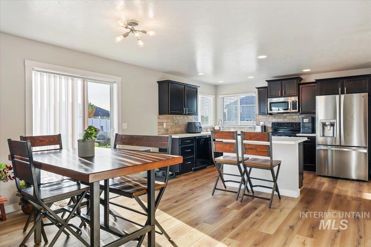 Kitchen featuring appliances with stainless steel finishes, light countertops, backsplash, a center island, and recessed lighting