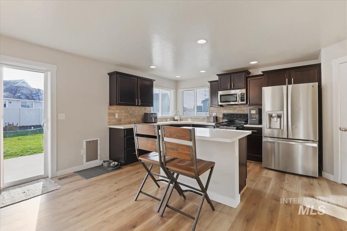 Kitchen featuring stainless steel appliances, dark brown cabinets, tasteful backsplash, light countertops, and recessed lighting