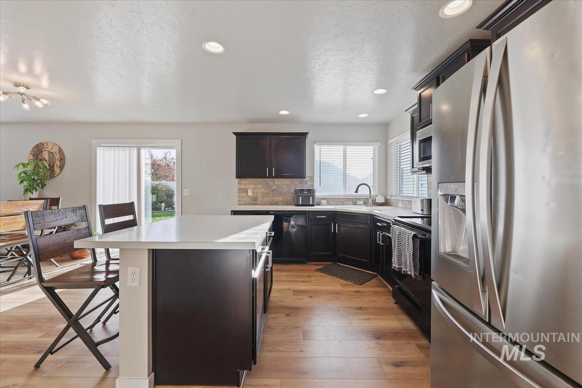 Kitchen with appliances with stainless steel finishes, light countertops, a breakfast bar, a kitchen island, and a textured ceiling