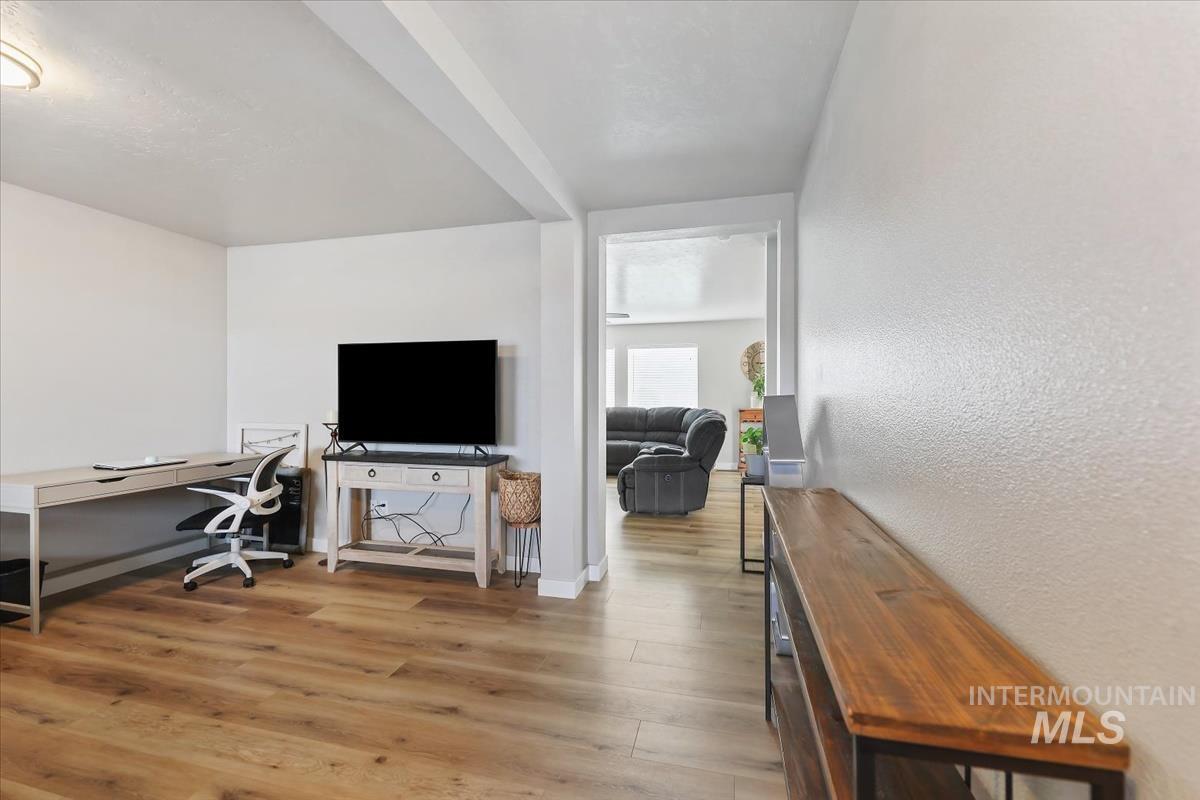 Office with light wood finished floors and a textured wall