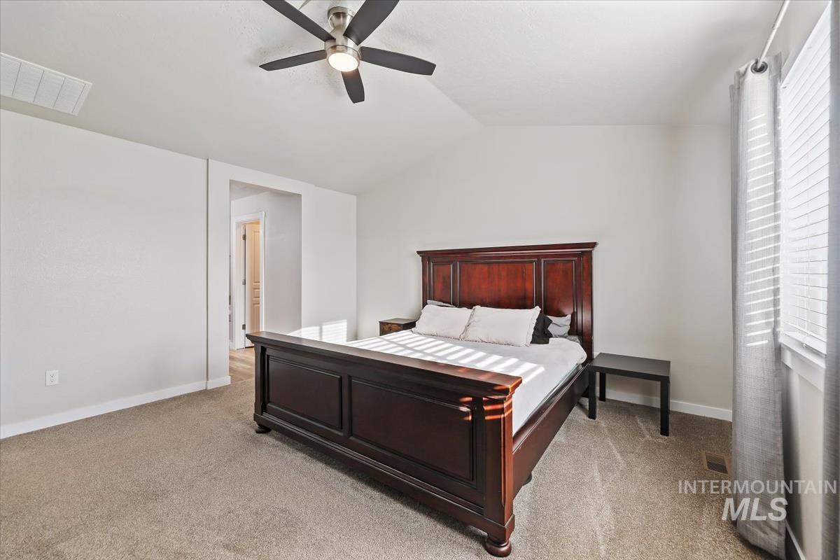 Bedroom featuring light colored carpet, vaulted ceiling, and ceiling fan