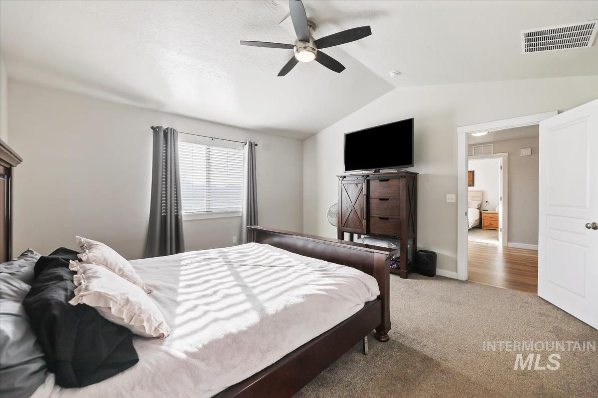 Carpeted bedroom featuring lofted ceiling and ceiling fan