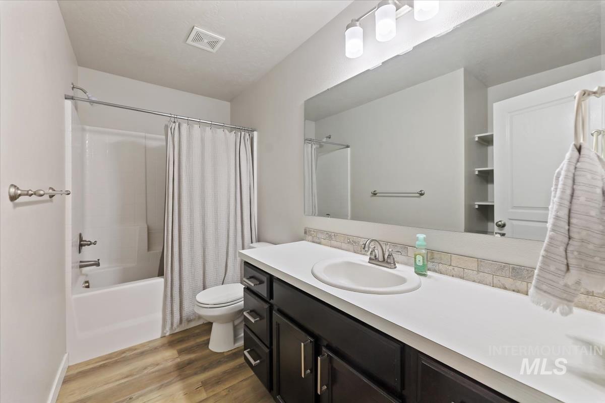 Bathroom with dark wood-style flooring, shower / tub combo, and vanity