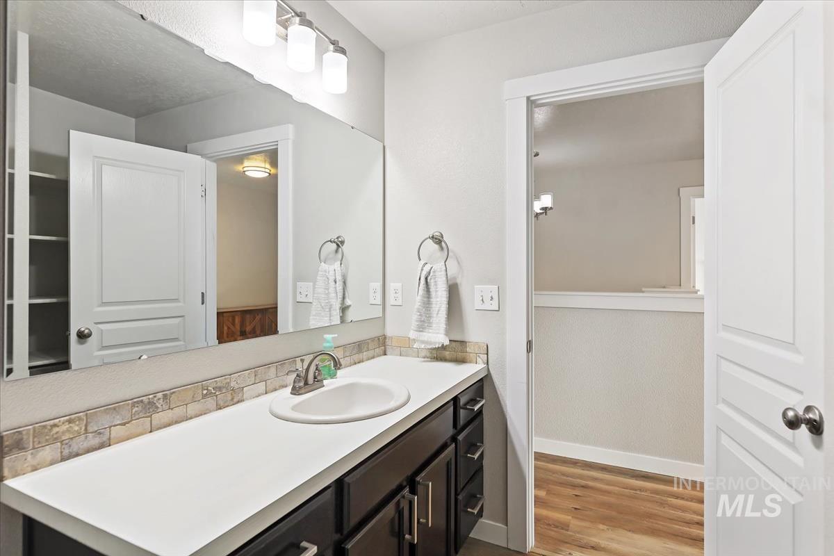 Bathroom featuring vanity, light wood-type flooring, and backsplash