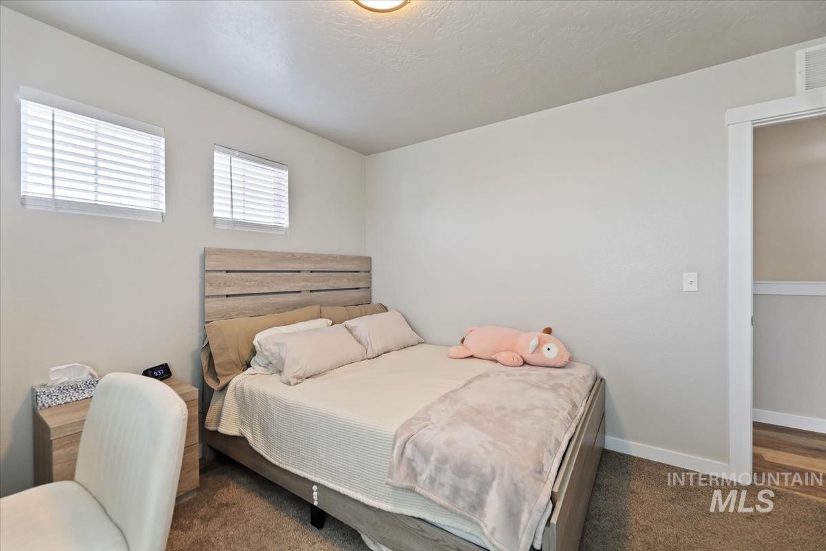 Bedroom with dark colored carpet and a textured ceiling