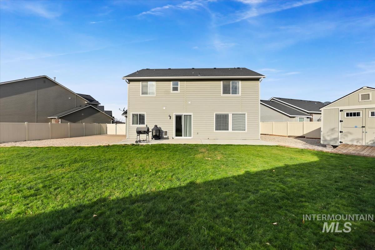 Rear view of house featuring a patio, a fenced backyard, and a storage shed