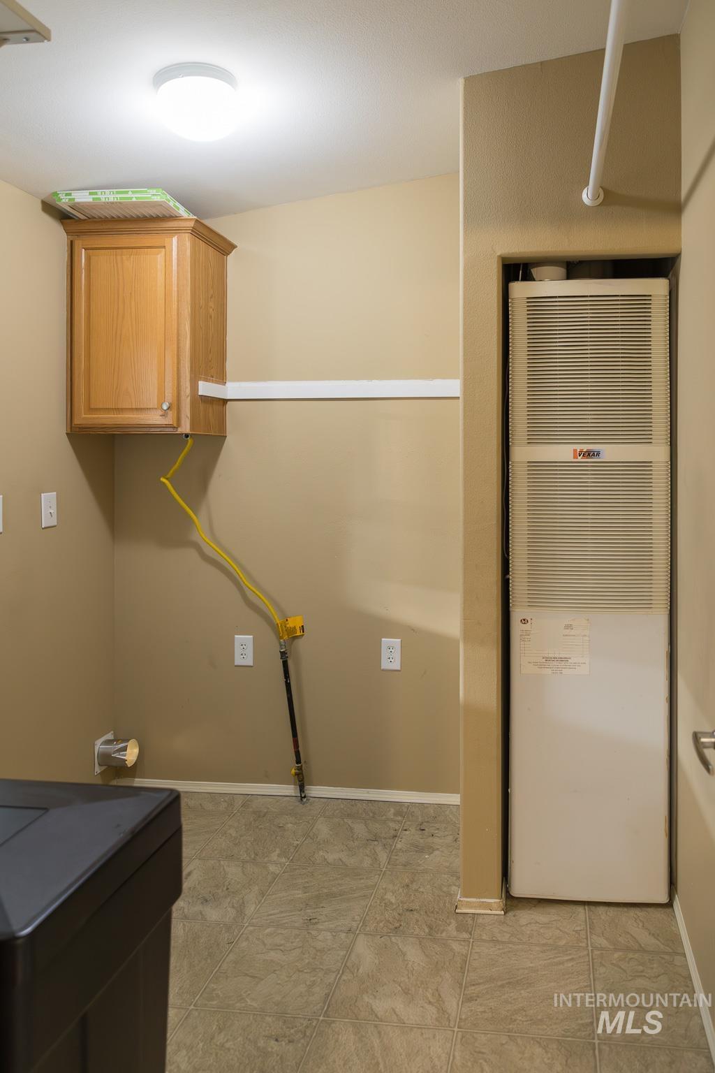 Laundry room featuring a heating unit and cabinet space