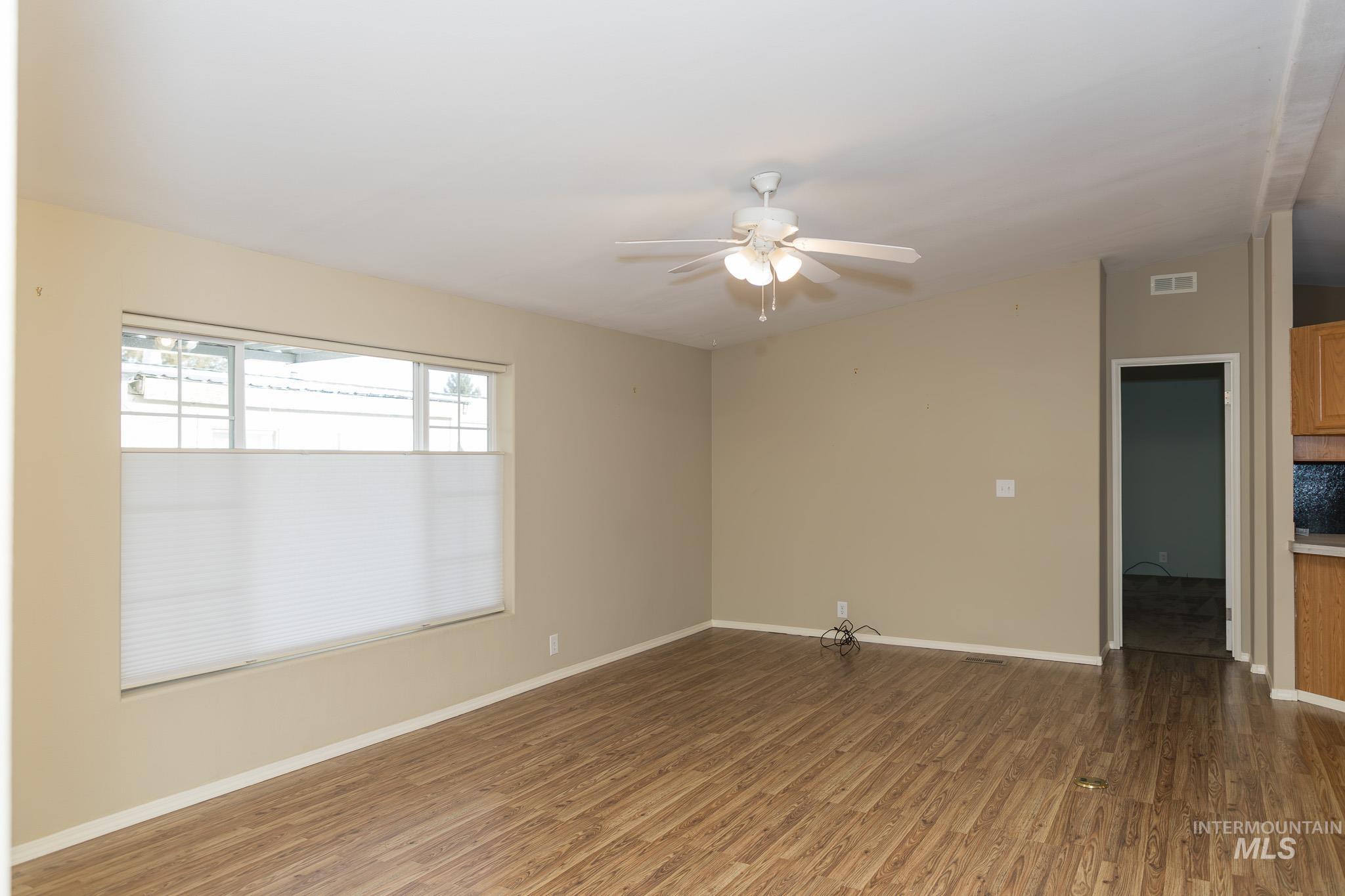 Empty room with dark wood-style flooring and a ceiling fan