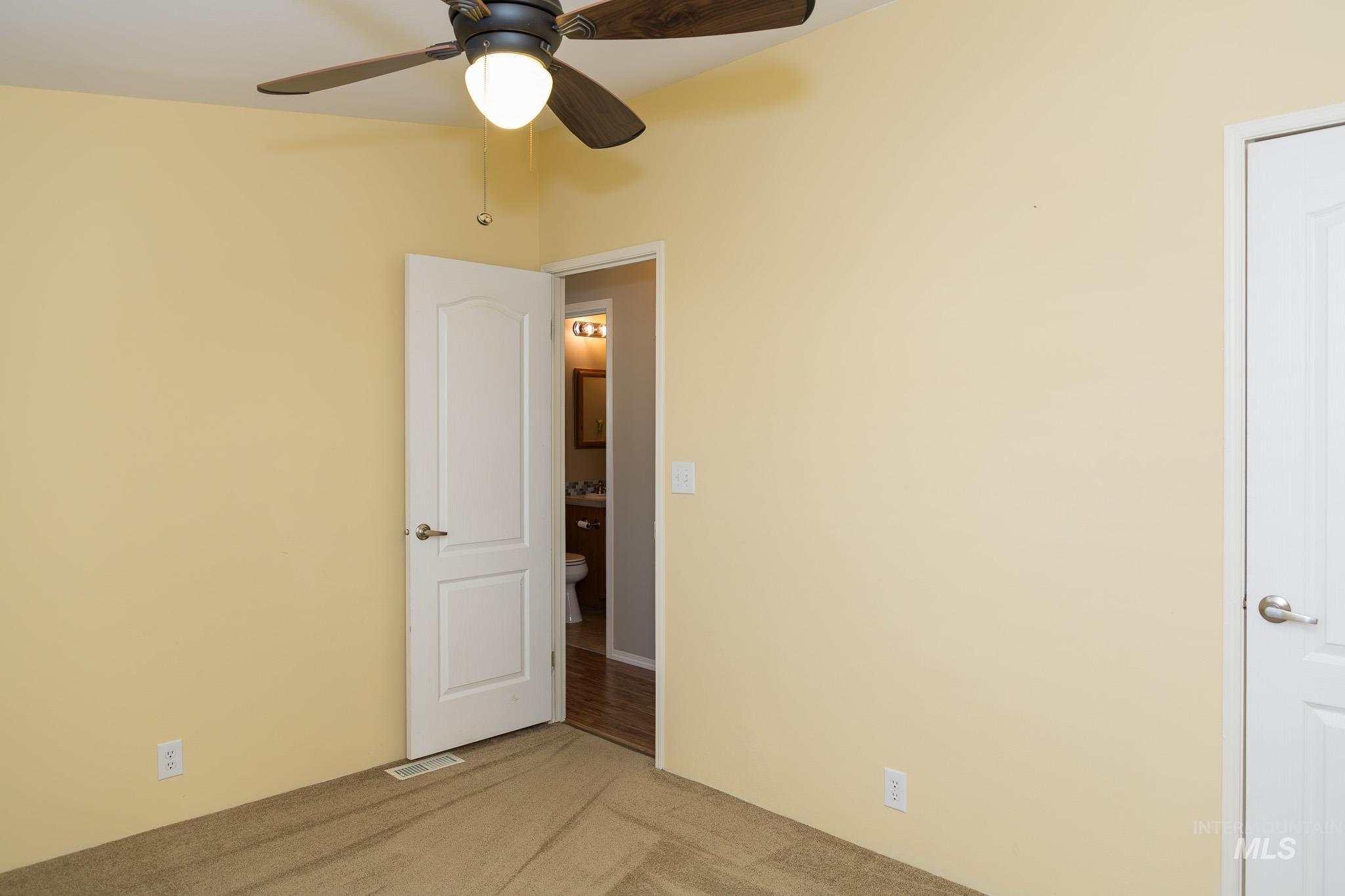 Spare room featuring carpet and ceiling fan
