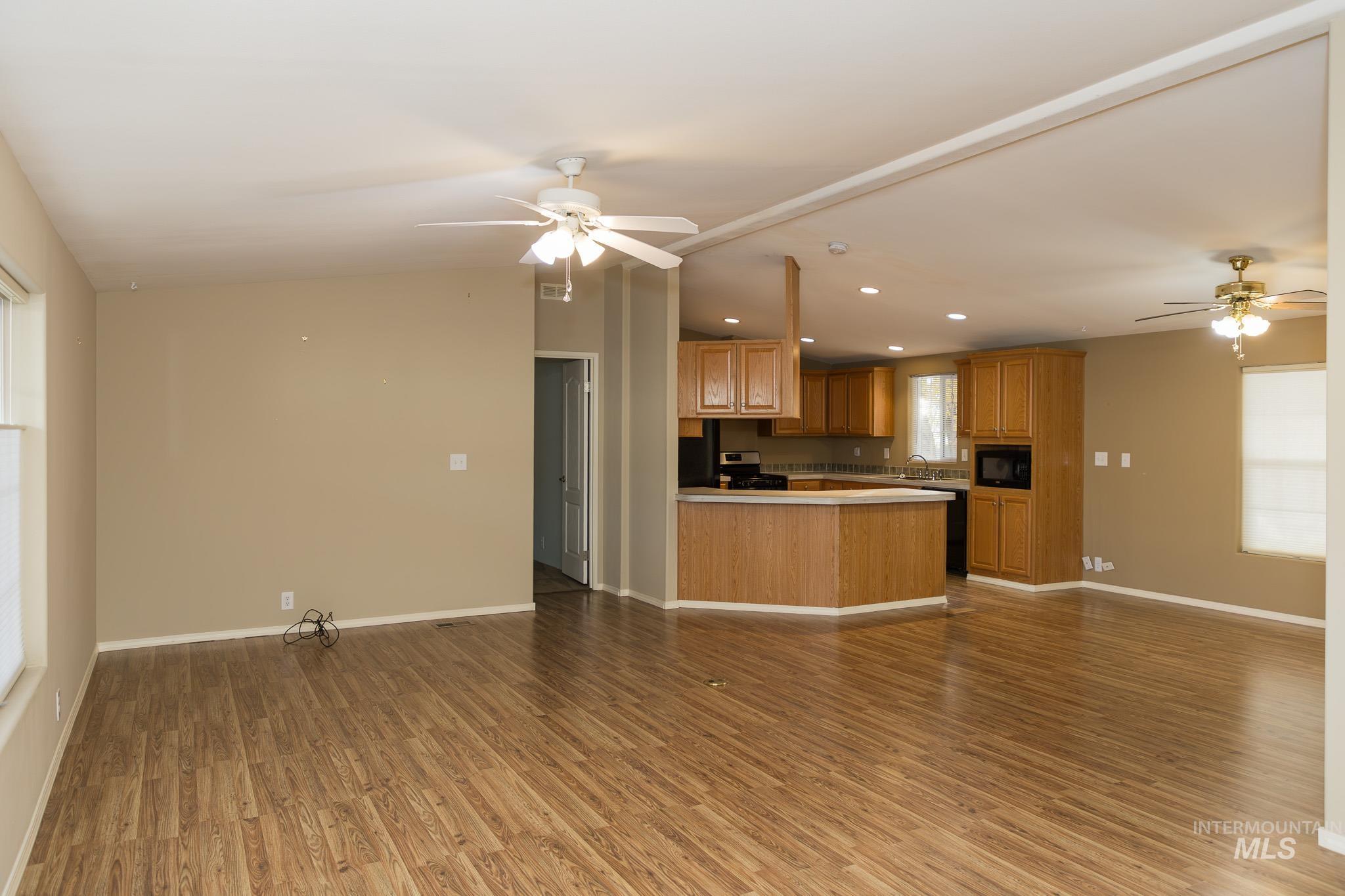 Kitchen with ceiling fan, open floor plan, recessed lighting, light wood finished floors, and vaulted ceiling