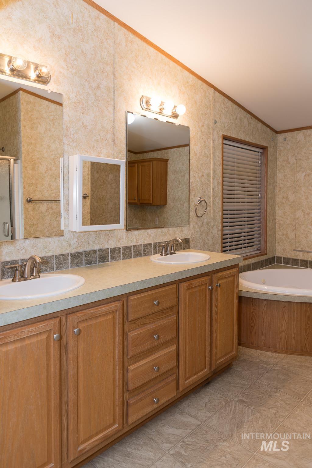 Full bathroom featuring double vanity, a garden tub, ornamental molding, a stall shower, and light tile patterned flooring