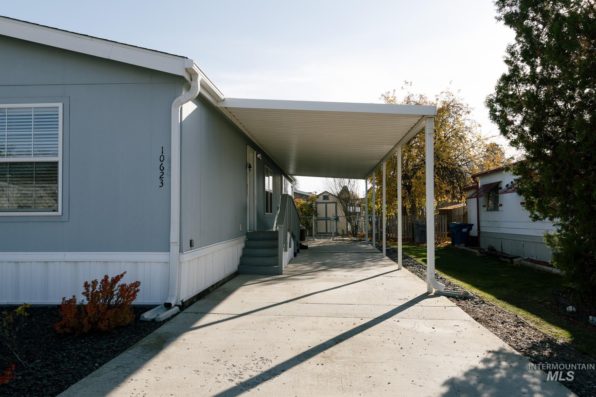 View of vehicle parking with a carport, a storage shed, driveway, and entry steps