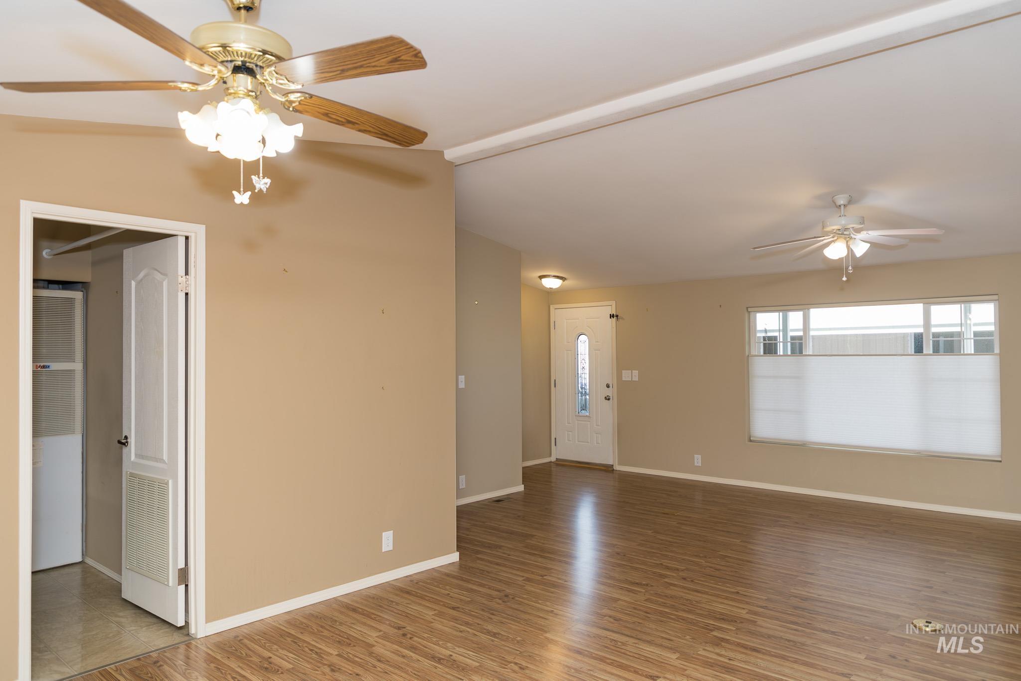 Unfurnished living room with a ceiling fan, light wood-type flooring, and lofted ceiling