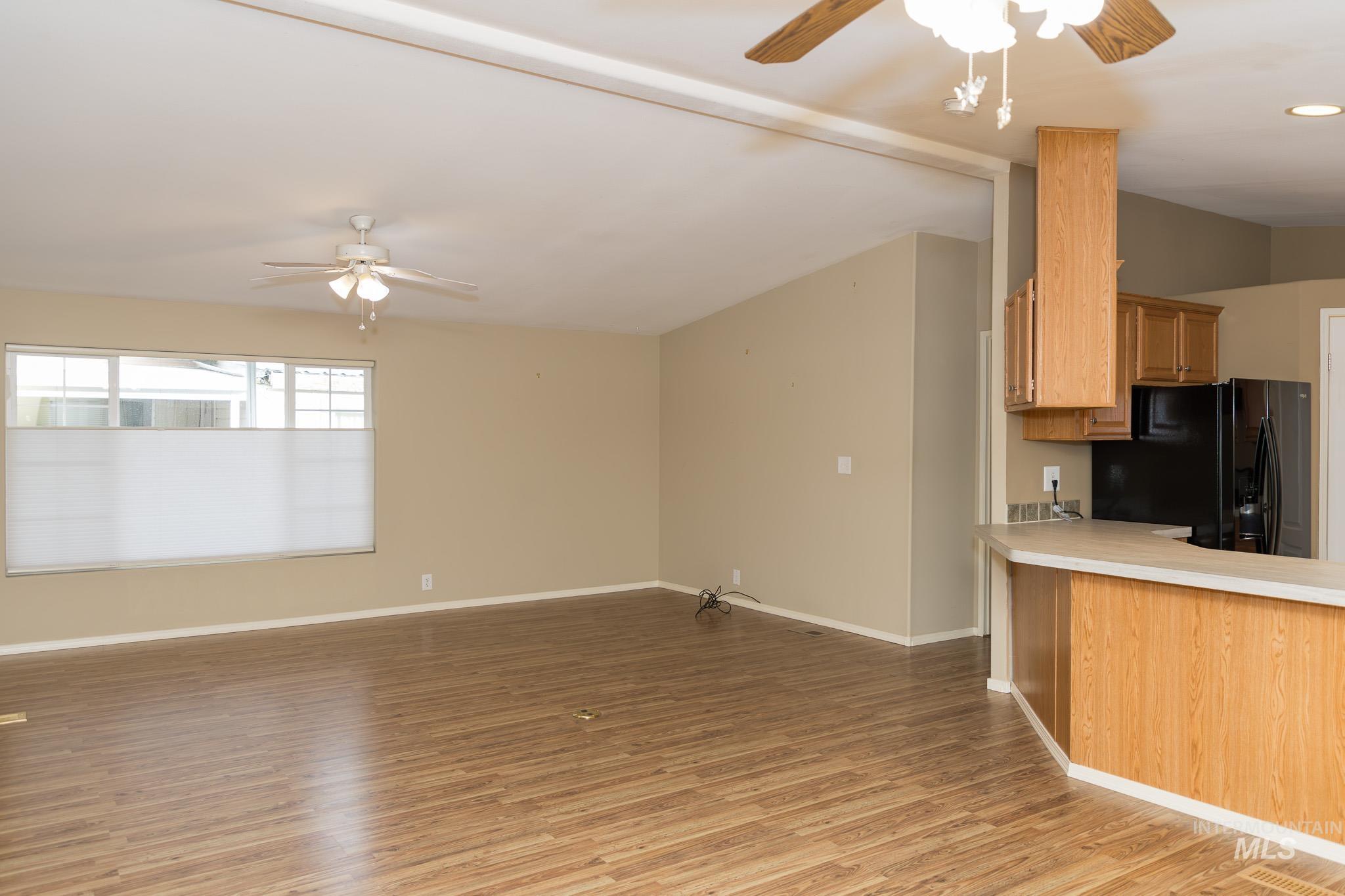 Kitchen with ceiling fan, open floor plan, light countertops, and light wood-style flooring