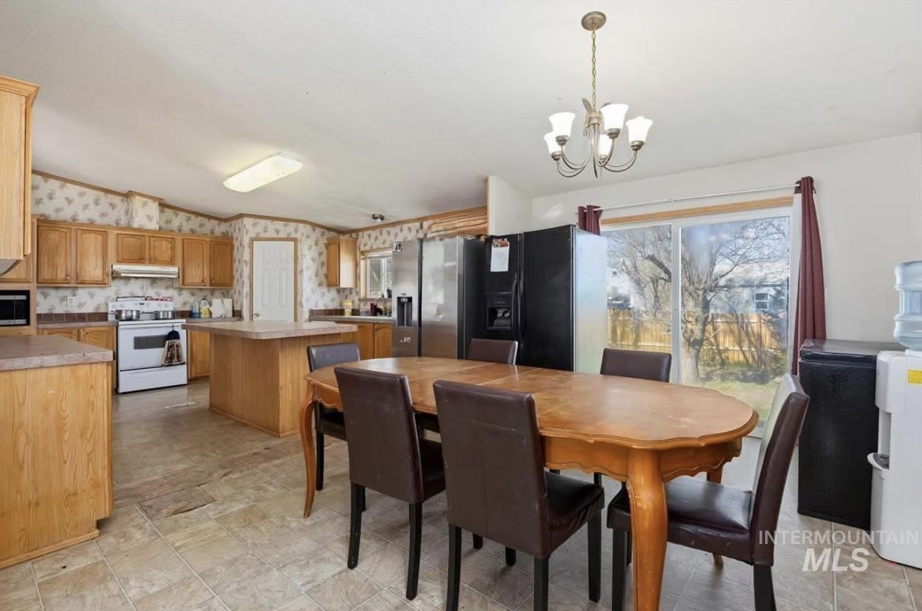 Dining room with wallpapered walls, vaulted ceiling, and a chandelier