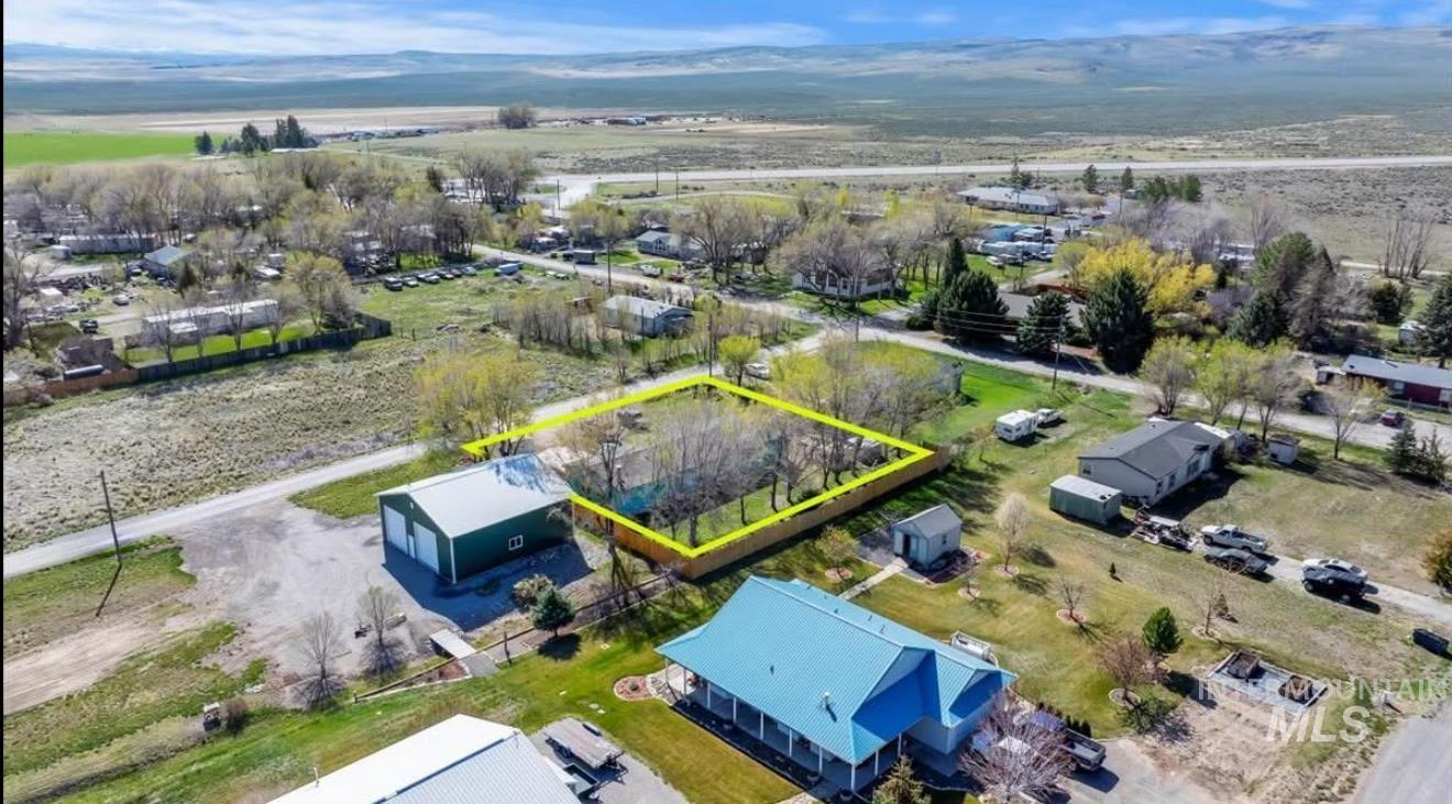 Aerial view of property and surrounding area with property boundaries highlighted and a mountain backdrop