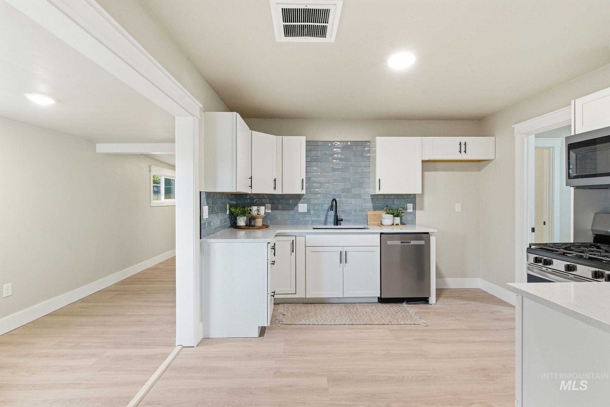 Kitchen featuring white cabinetry, backsplash, stainless steel appliances, and recessed lighting