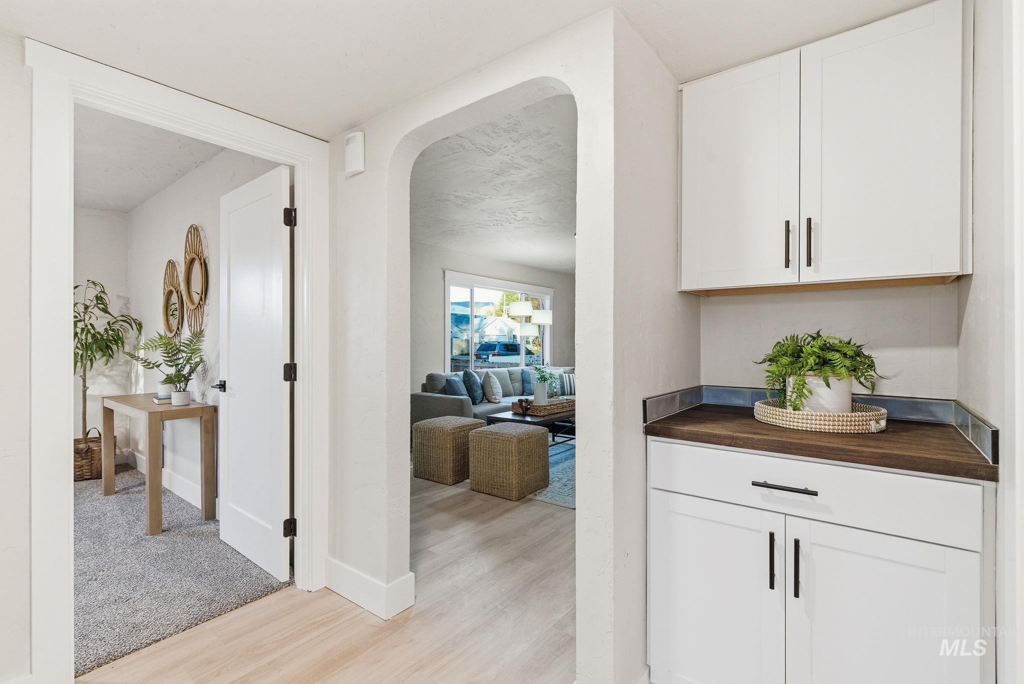 Hallway featuring arched walkways and light wood finished floors