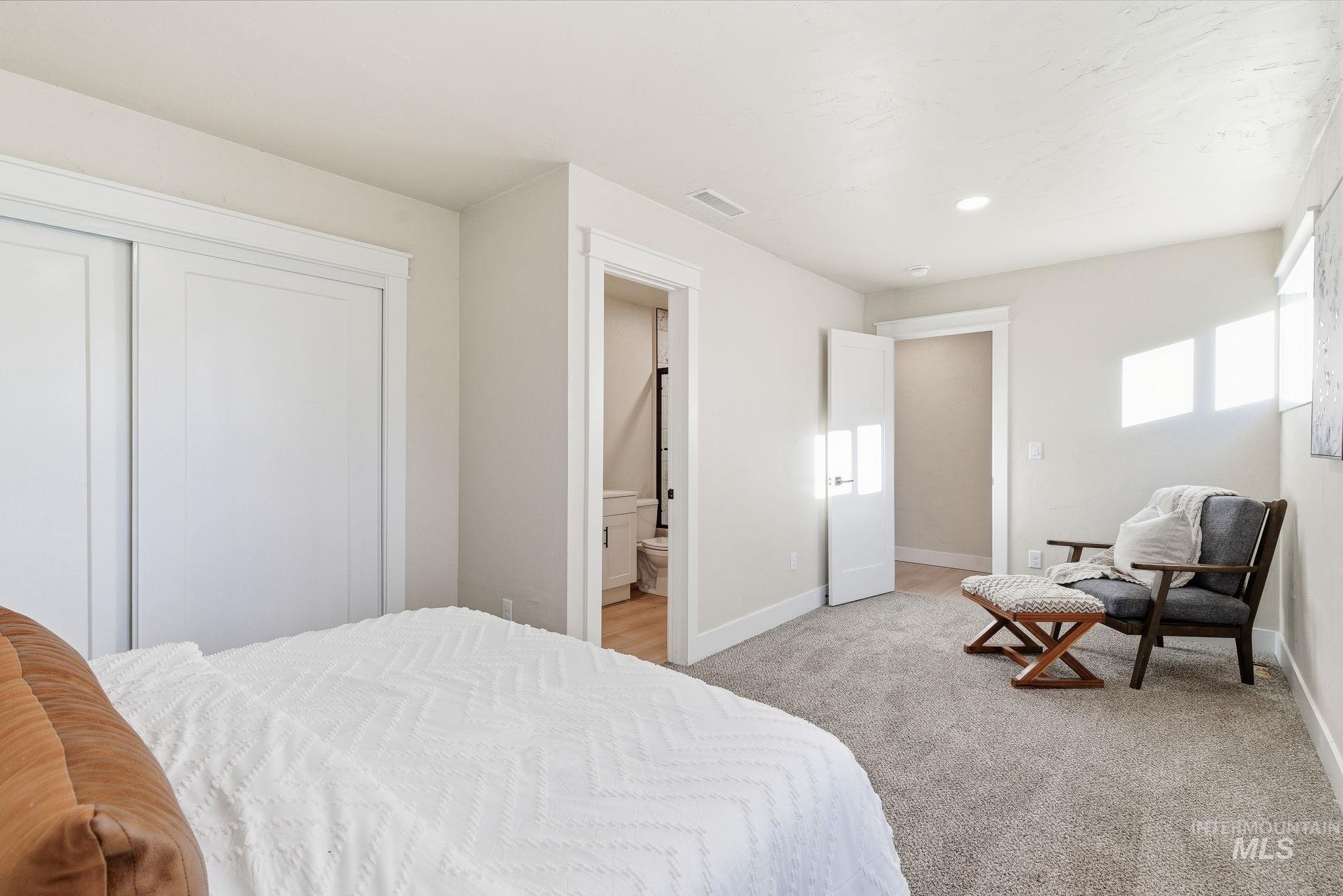 Bedroom with light colored carpet, a closet, recessed lighting, and ensuite bathroom
