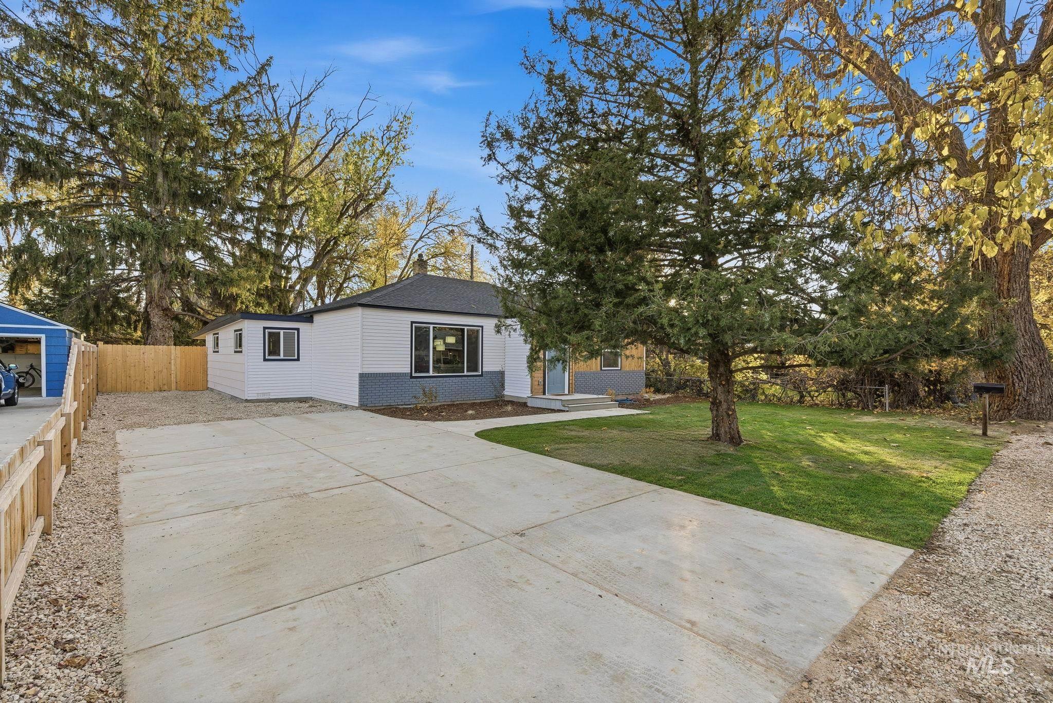 View of front of house with driveway, a patio area, and roof with shingles