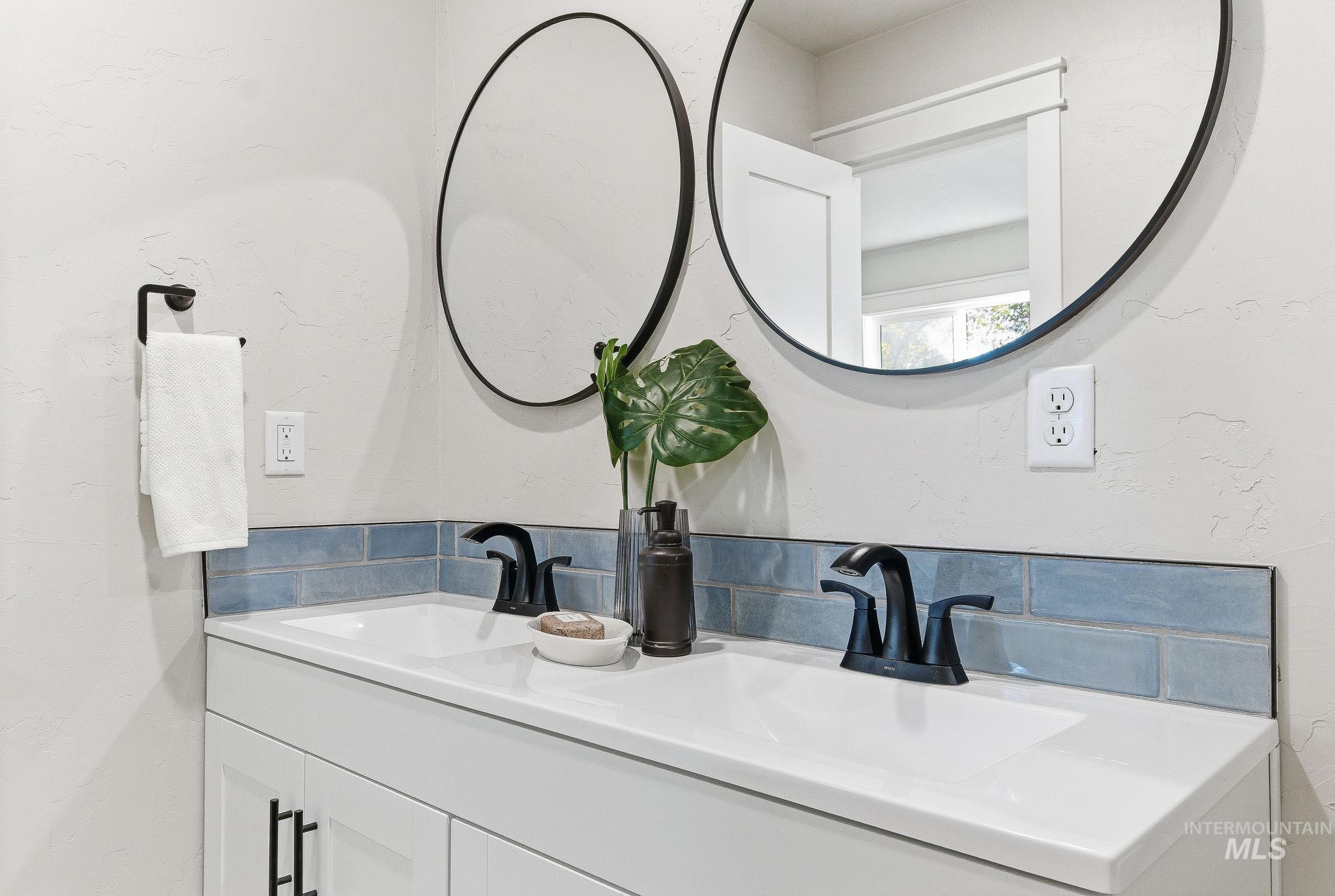 Bathroom with double vanity, a textured wall, and backsplash