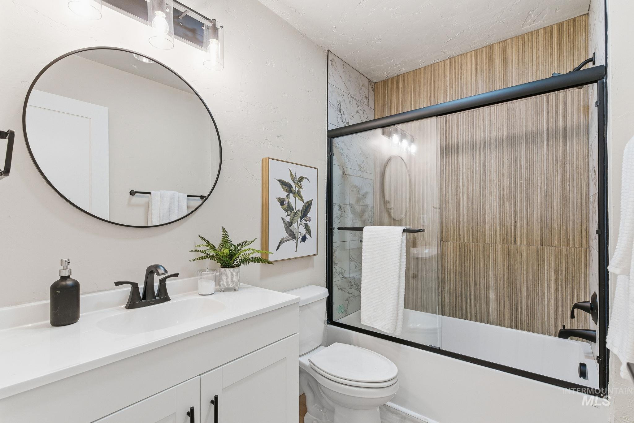 Full bathroom with vanity and enclosed tub / shower combo
