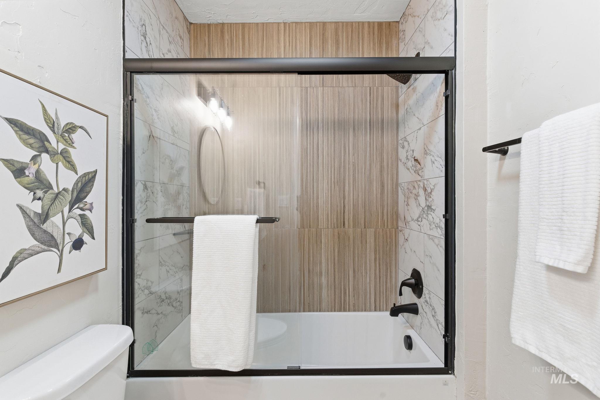 Bathroom featuring shower / bath combination with glass door and toilet