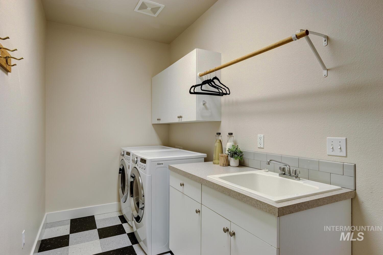 Laundry area with washing machine and dryer, light flooring, and cabinet space