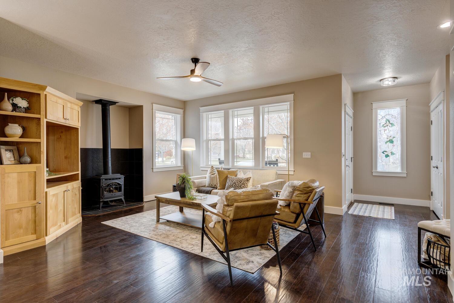 Living room with a wood stove, a textured ceiling, plenty of natural light, and dark wood-type flooring
