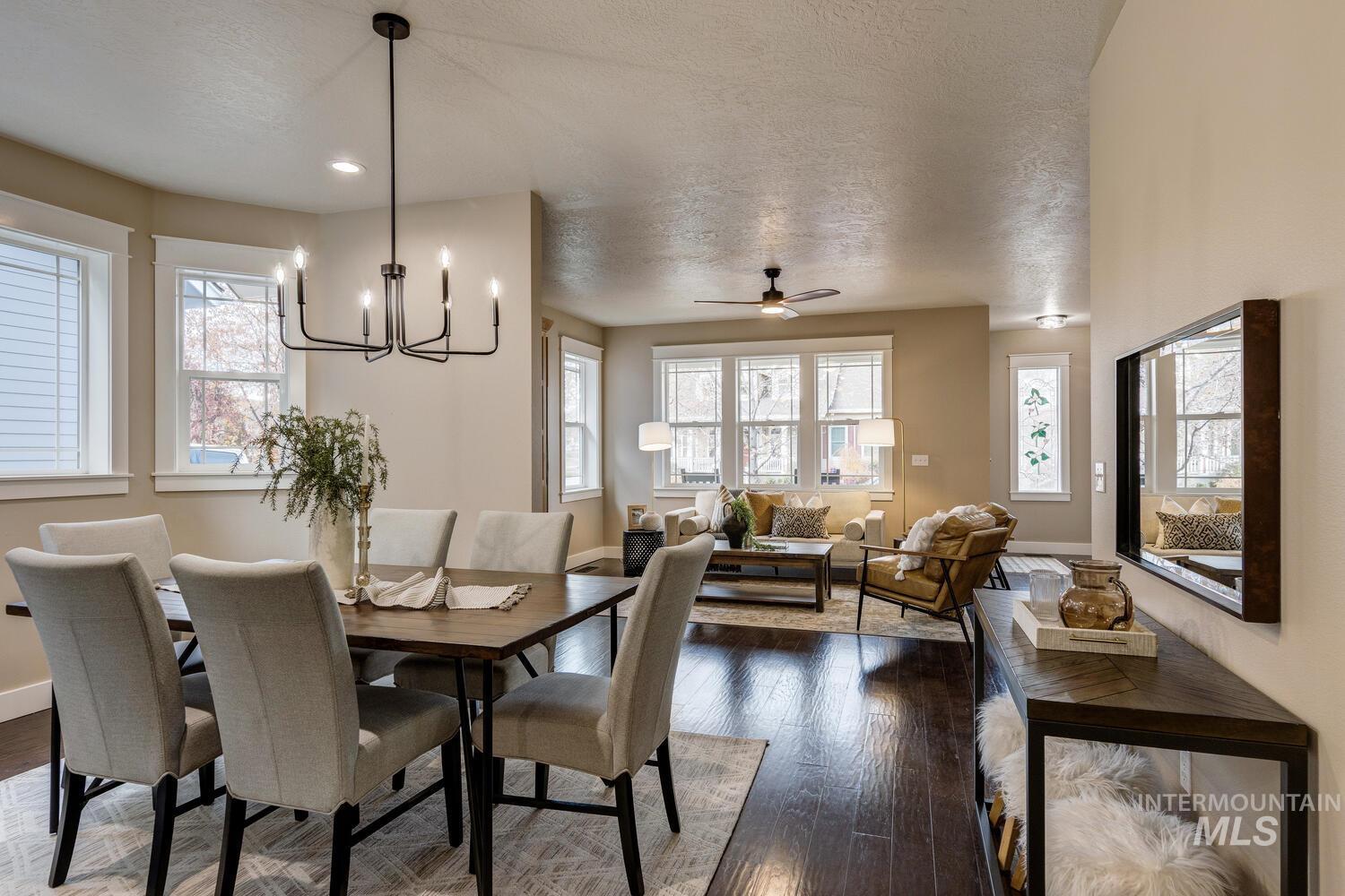 Dining area featuring a textured ceiling, dark wood-type flooring, healthy amount of natural light, a ceiling fan, and a chandelier