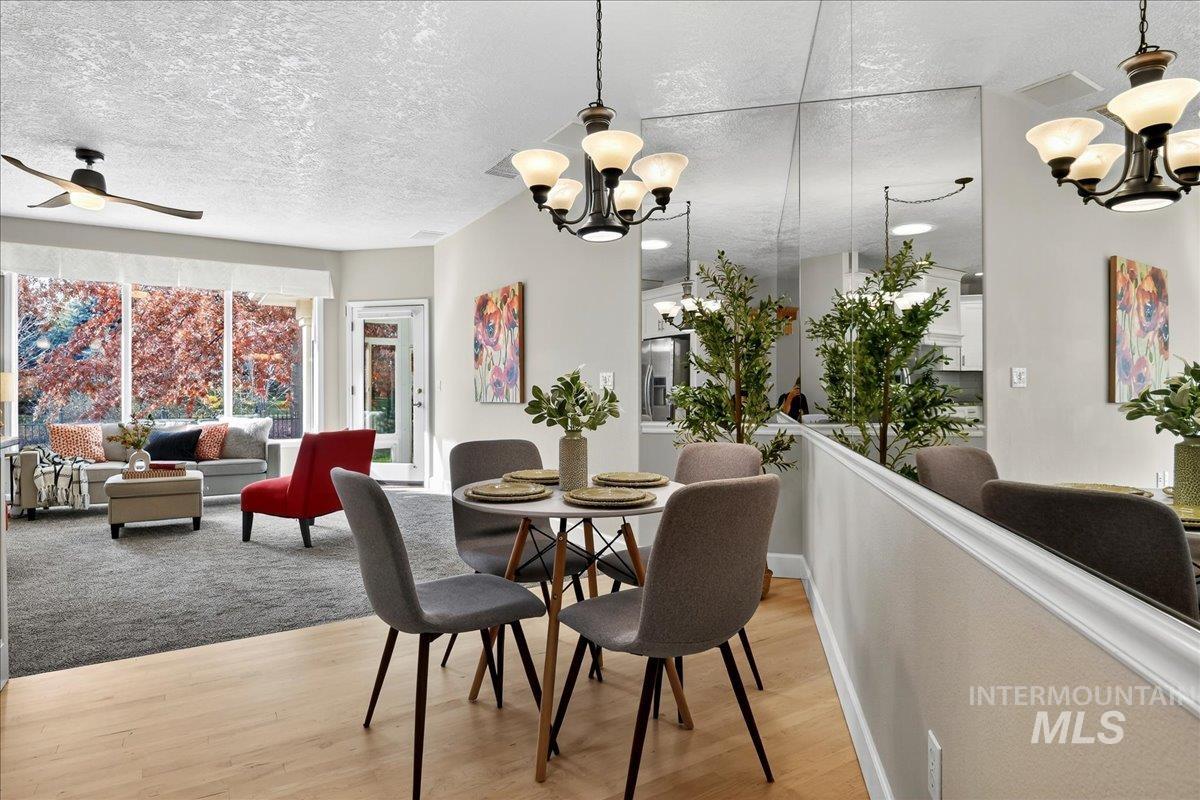 Dining area with a chandelier, light wood-style flooring, a textured ceiling, and a ceiling fan