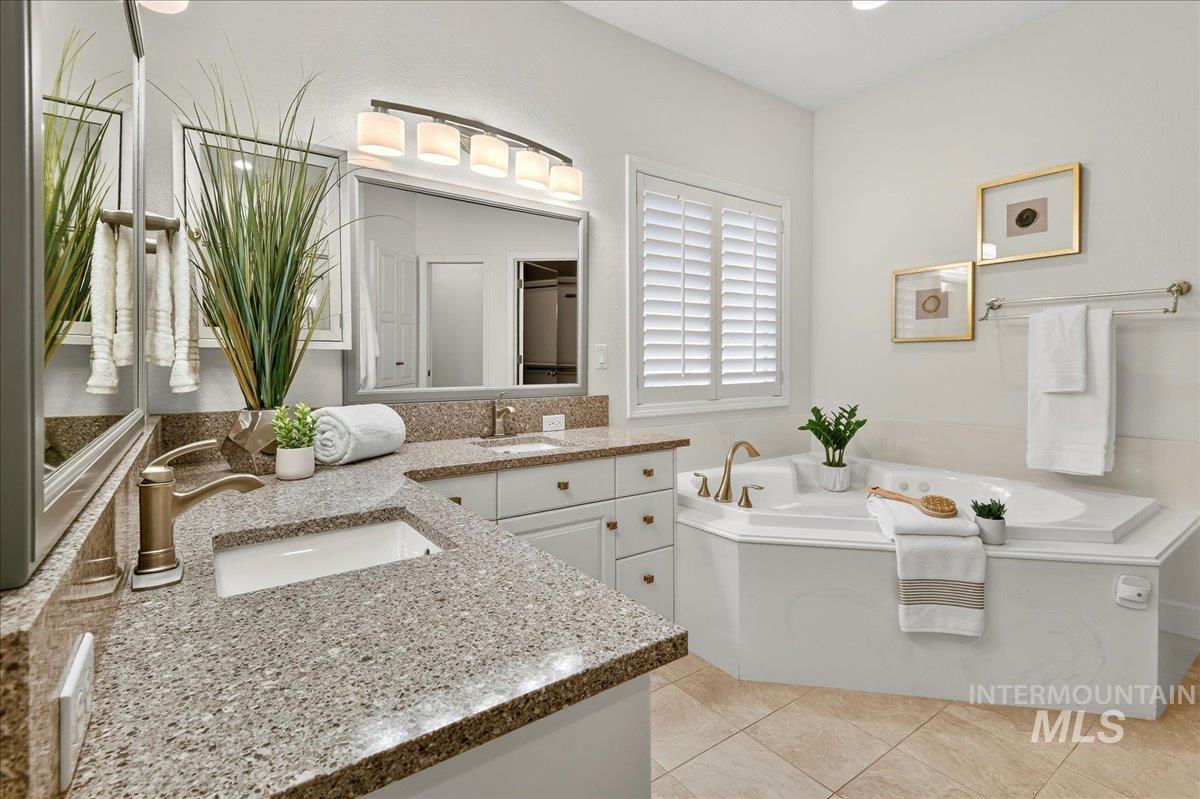 Full bathroom featuring double vanity, a garden tub, and light tile patterned floors