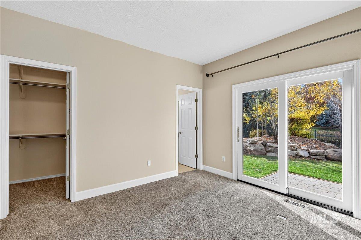 Unfurnished bedroom with light colored carpet, a walk in closet, and access to exterior
