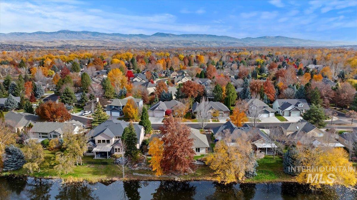 Aerial view of property and surrounding area featuring nearby suburban area and a water and mountain view