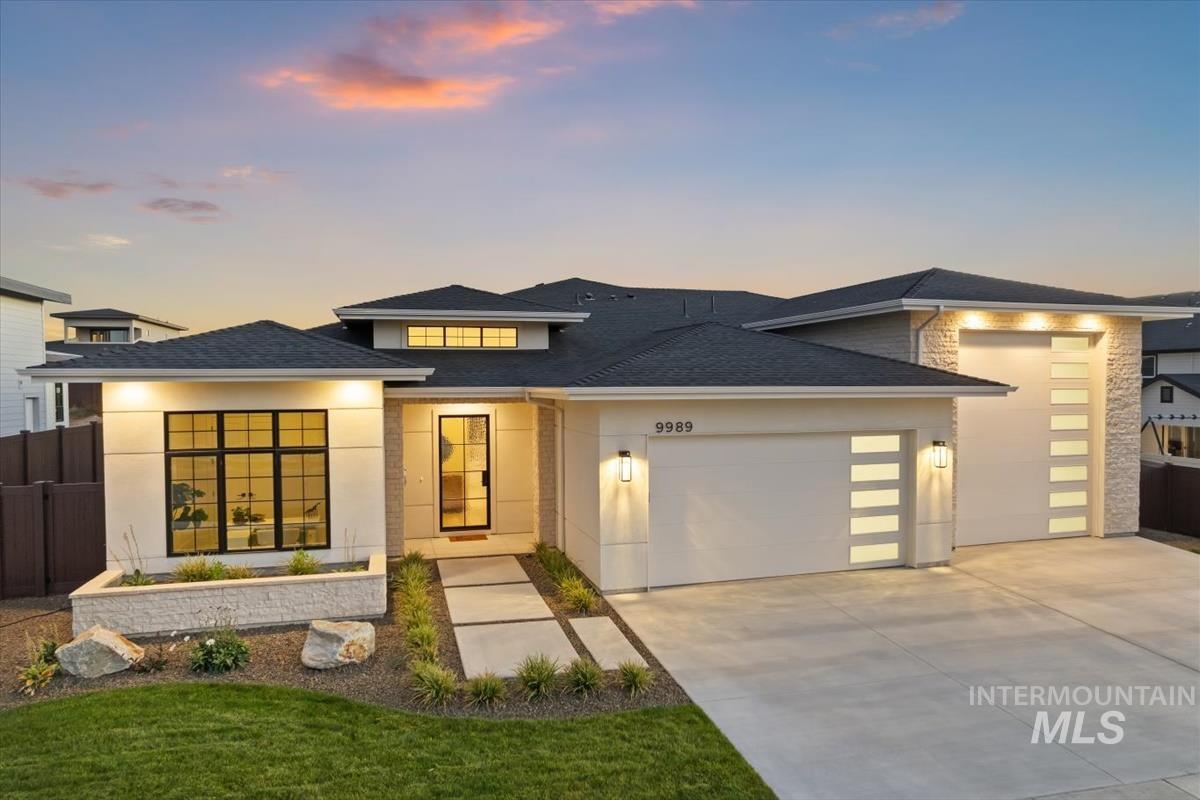 View of front of house with a garage, concrete driveway, and a shingled roof
